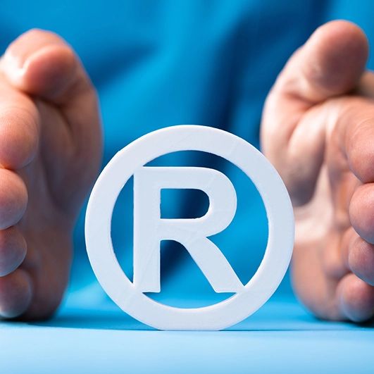 A professional seated at a desk carefully protects the registered trademark symbol, symbolizing the importance of intellectual property in today's competitive market